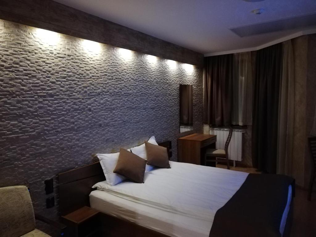 - une chambre avec un lit et un mur en briques dans l'établissement HQ apartments Villa Park, à Borovets