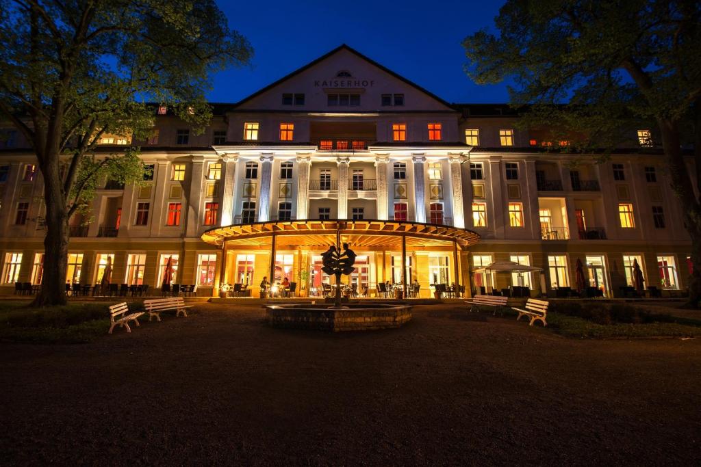 a large building with benches in front of it at night at Kulturhotel Kaiserhof in Bad Liebenstein