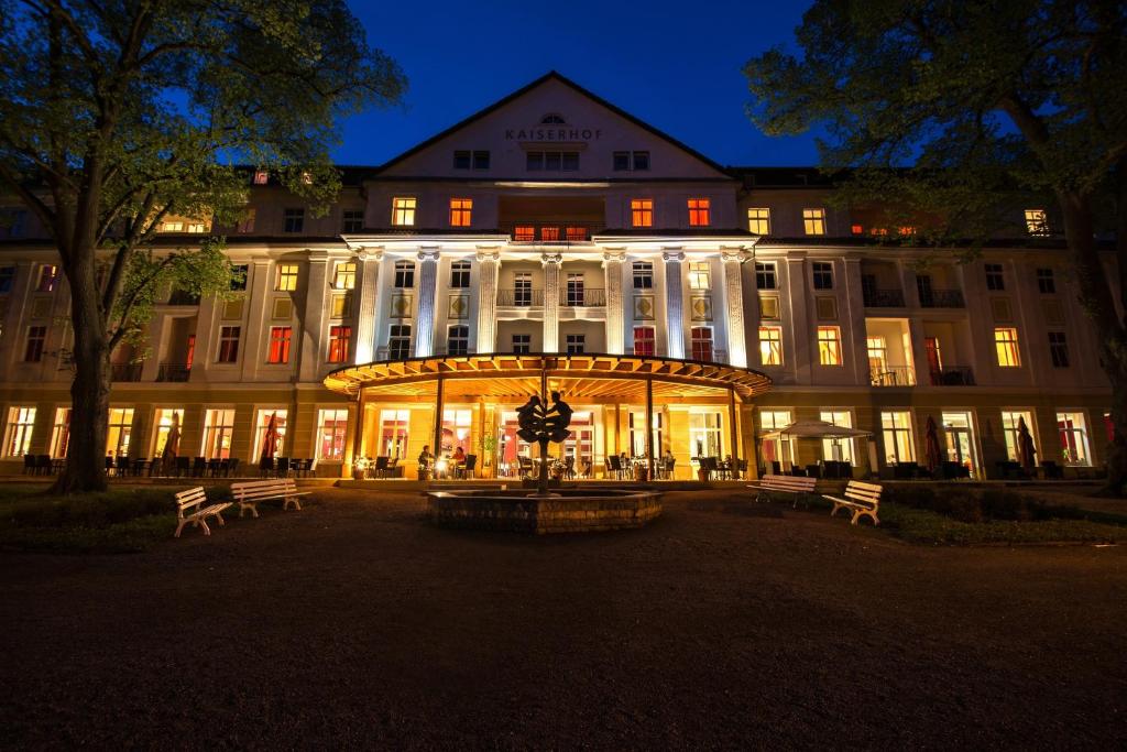 ein großes Gebäude mit Bänken in der Nacht davor in der Unterkunft Kulturhotel Kaiserhof in Bad Liebenstein