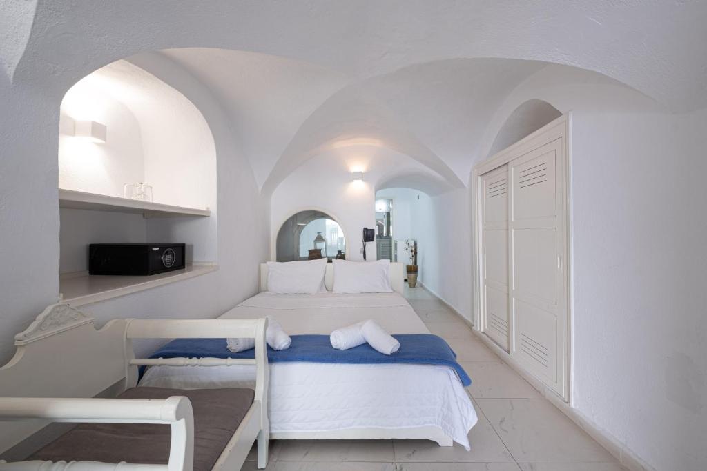 a white bedroom with a large bed in a room at Loucas on the Cliff in Fira