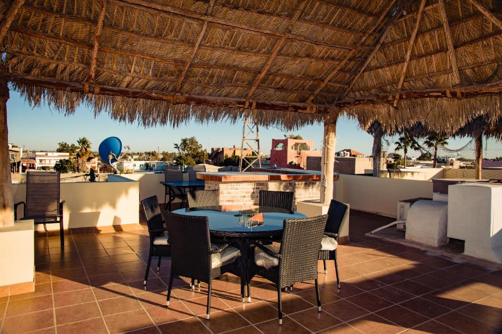 eine Terrasse mit einem Tisch und Stühlen sowie einem Strohdach in der Unterkunft Bella Vista 6 in Puerto Peñasco