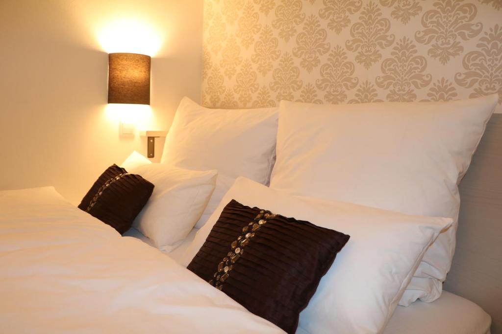 two beds in a hotel room with white pillows at List Five - Your British Guesthouse in Stuttgart