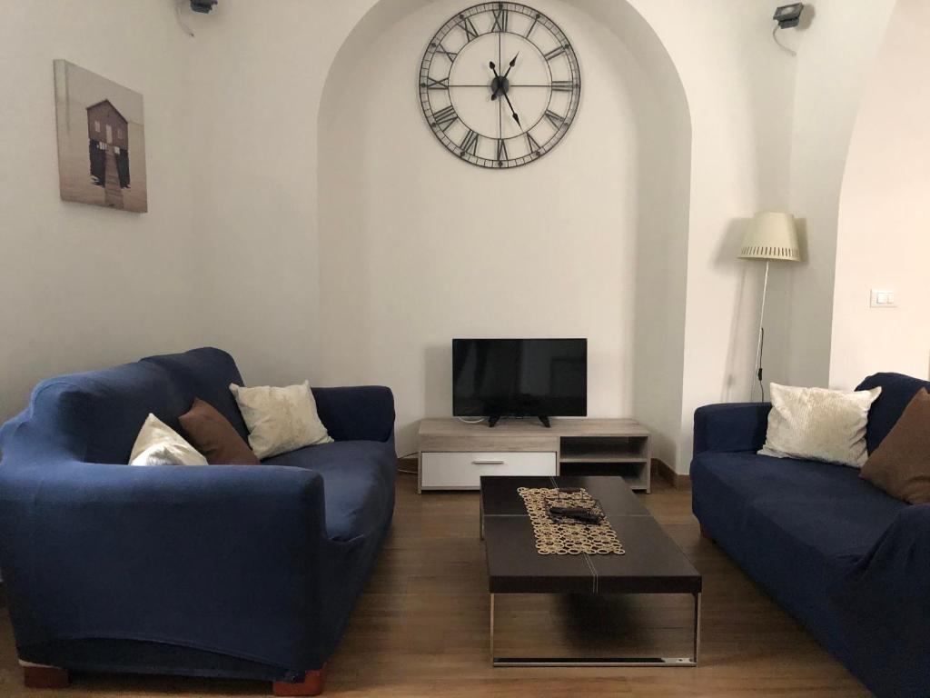 a living room with two blue couches and a clock on the wall at Elle's House in Savona