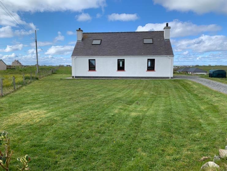 a large white house with a large grass yard at 18 Cross Skigesrta Road in Swanibost