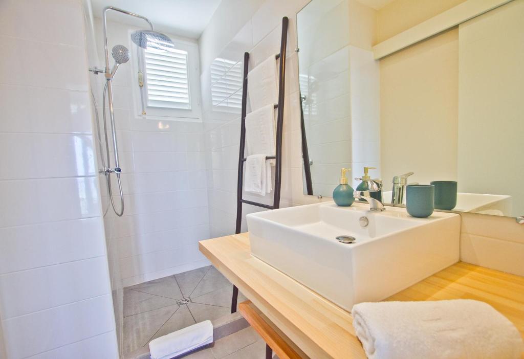 a white bathroom with a sink and a shower at Cannelle in Deshaies