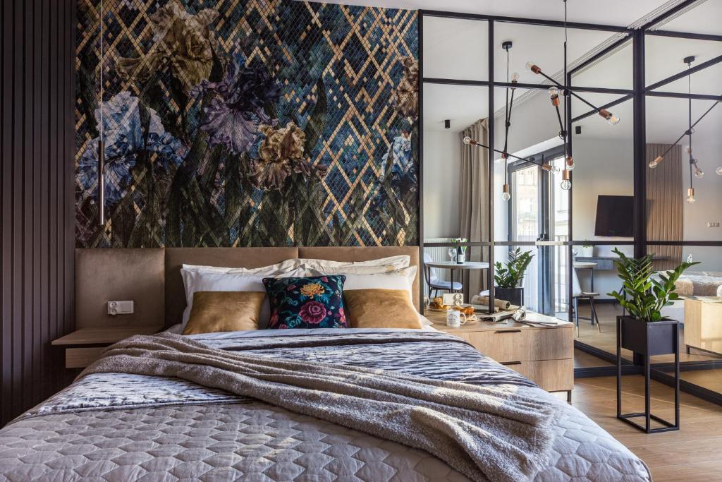 a bedroom with a bed and a wall with a painting at Fragola Apartments Rajska 3 - modern studios, park in Kraków