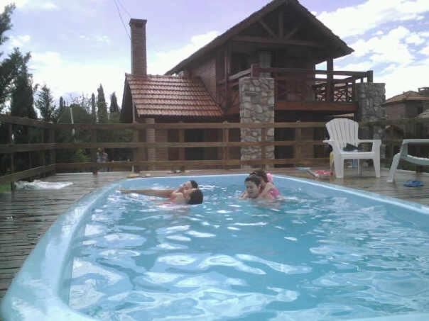 un par de personas nadando en una piscina en CABAÑAS JACARANDA en Merlo