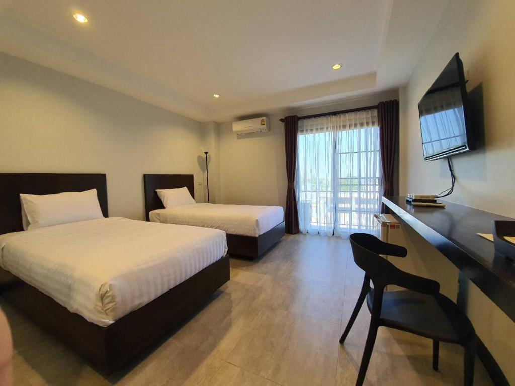 Habitación de hotel con 2 camas, escritorio y TV. en T-NEE Hotel@Udon en Udon Thani