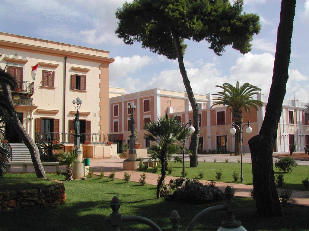 un grand bâtiment avec des palmiers devant lui dans l'établissement Grand Hotel Palace, à Marsala