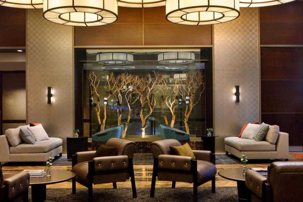 a lobby with couches chairs tables and a wall mural at The Muse New York in New York
