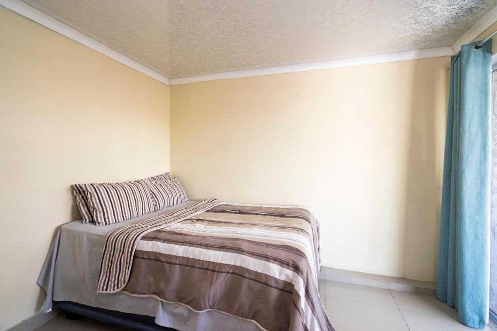 1 dormitorio con 1 cama con manta y ventana en Hasate Guest House 10 Florence street Oakdale Belliville 7530 cape town south African, en Ciudad del Cabo