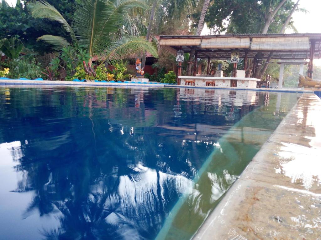 a swimming pool with the reflection of a house in the water at Ritinula Resort in Tejakula