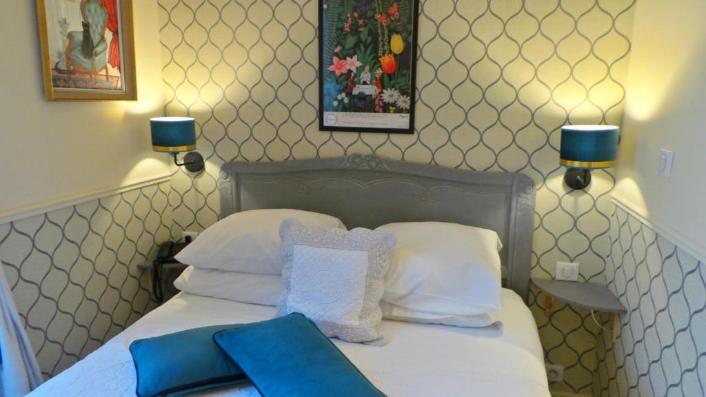 a bedroom with a bed with two blue pillows at Hotel Relais Du Postillon in Antibes