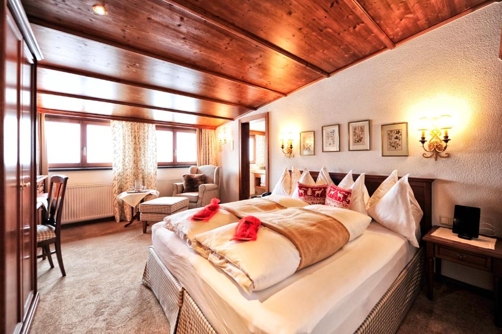 ein Schlafzimmer mit einem großen Bett mit roten Bögen darauf in der Unterkunft Haldenhof in Lech am Arlberg