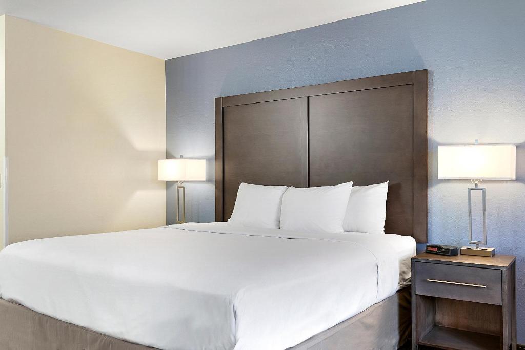 un grande letto bianco in una camera d'albergo con due lampade di Days Inn by Wyndham Ellensburg a Ellensburg