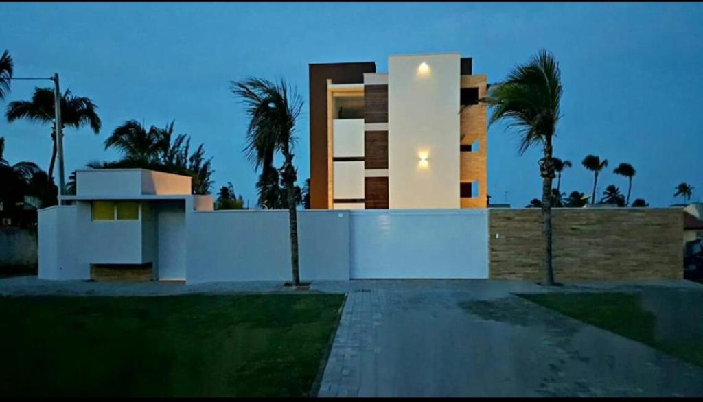 a building with palm trees in front of it at Residence Taormina no Cumbuco in Cumbuco