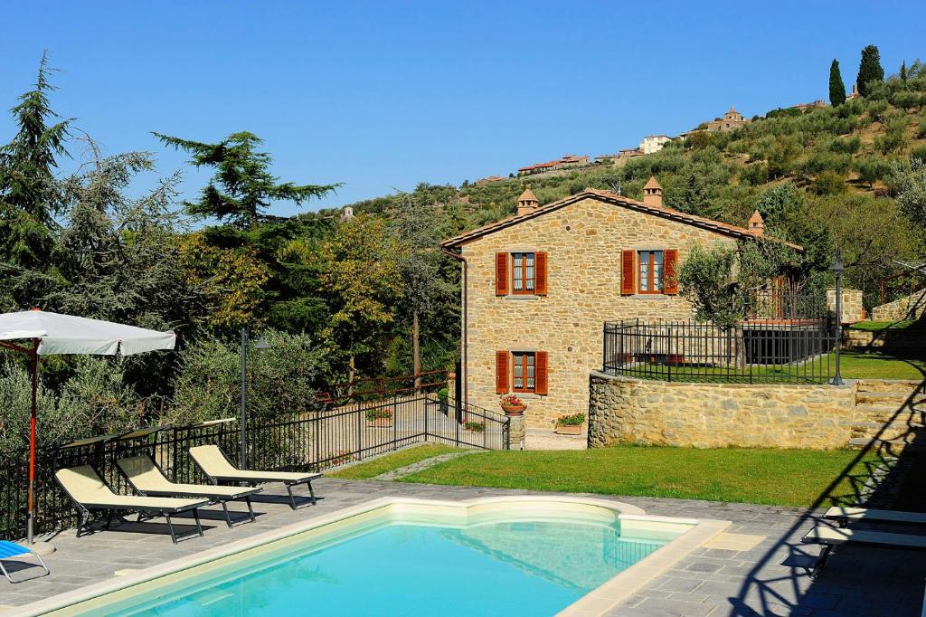 uma casa com piscina em frente a uma casa em Agriturismo Il Torrino em Cortona