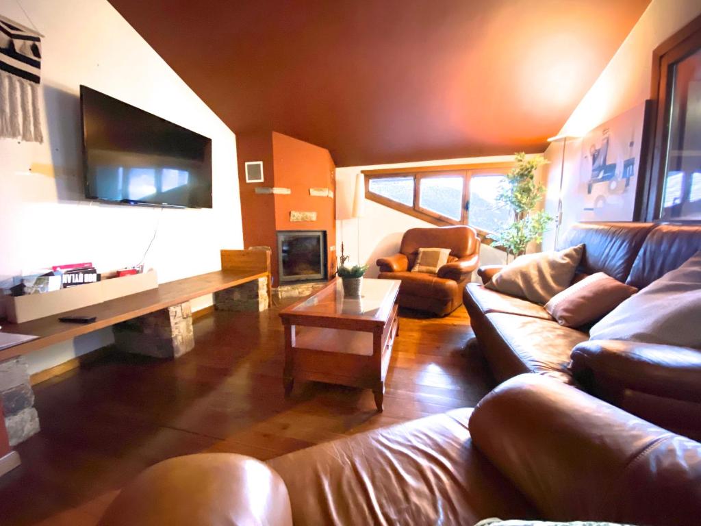 a living room with leather couches and a tv at Isards, Atico rustico con chimenea en el tarter, zona Grandvalira in El Tarter