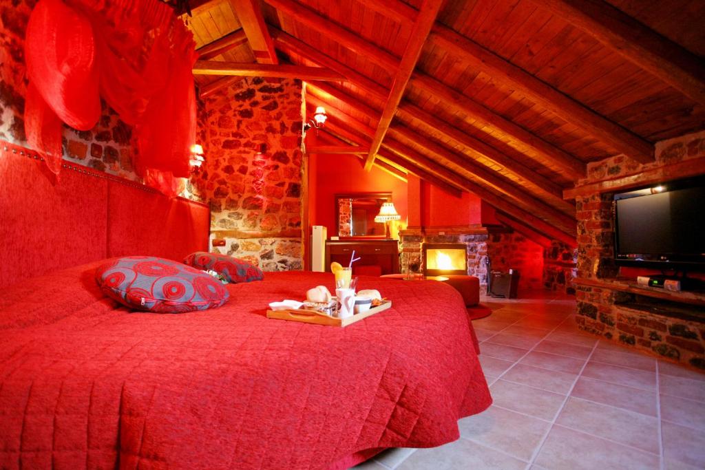 um quarto com uma cama vermelha e uma televisão em Patriko Mountain Chalet em Palaios Agios Athanasios