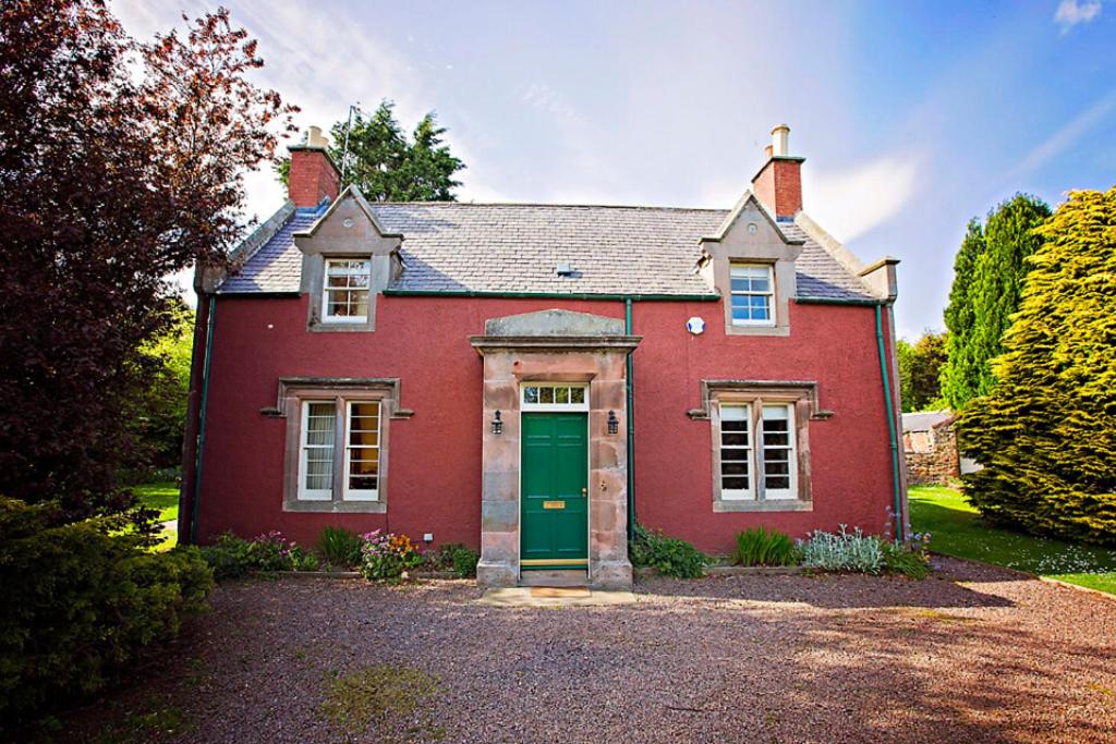 ein rotes Backsteinhaus mit einer grünen Tür in der Unterkunft The Head Gardeners Cottage, Dunbar in Dunbar