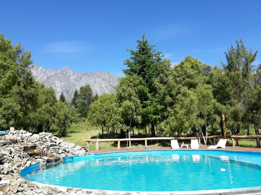 una piscina con árboles y montañas en el fondo en Del Viejo Camino en El Bolsón