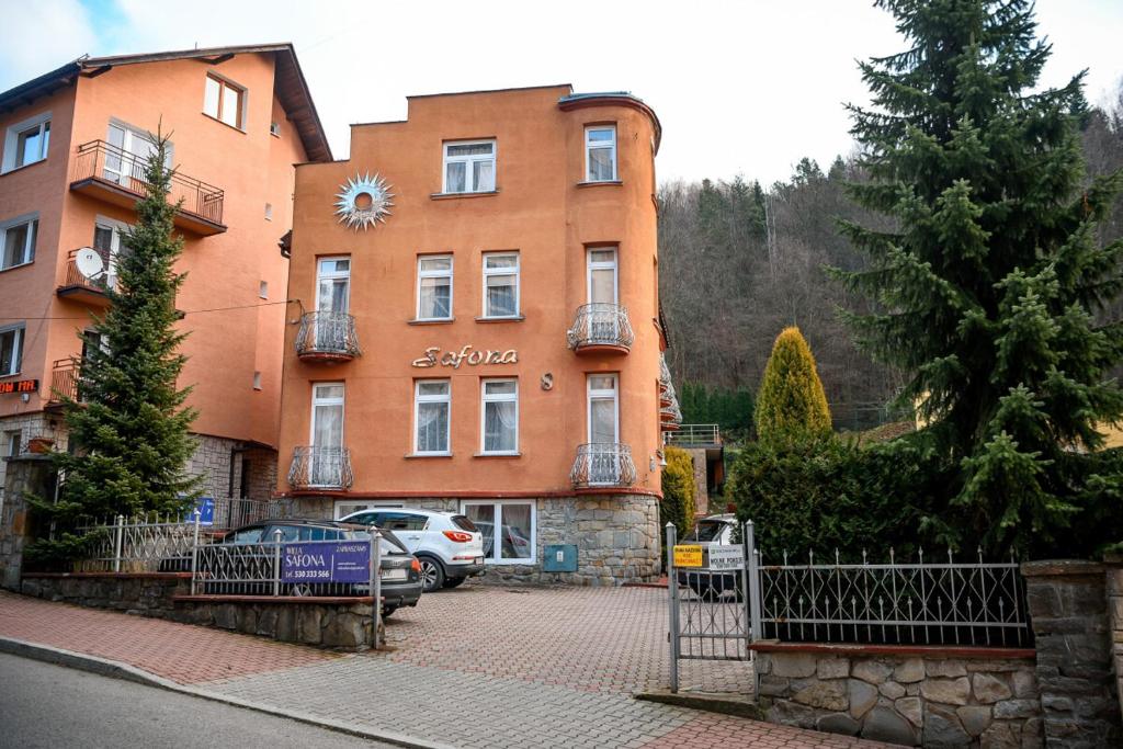 a large orange building with a gate in front of it at Willa Safona in Krynica Zdrój