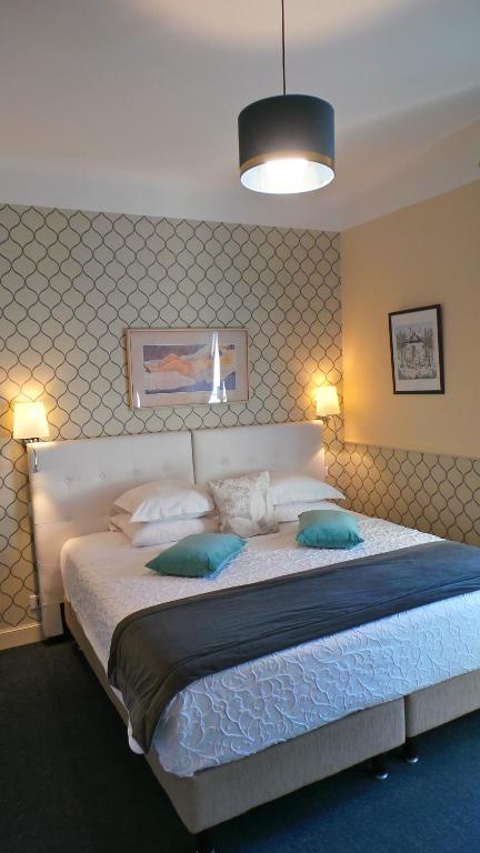a bedroom with a large white bed with blue pillows at Hotel Relais Du Postillon in Antibes