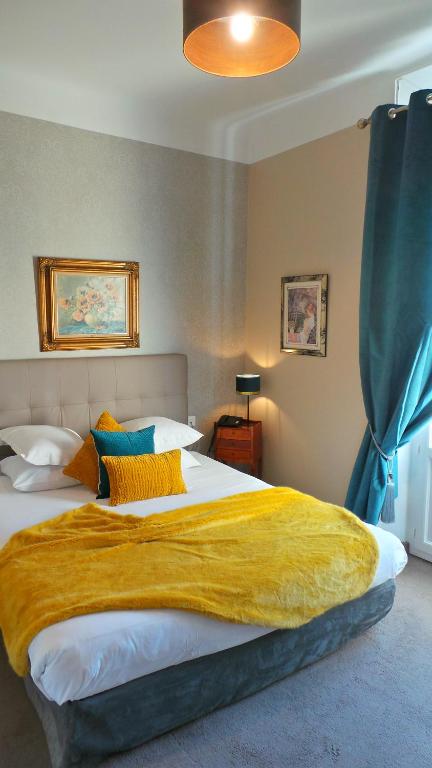 a bedroom with a large bed with a yellow blanket on it at Hotel Relais Du Postillon in Antibes