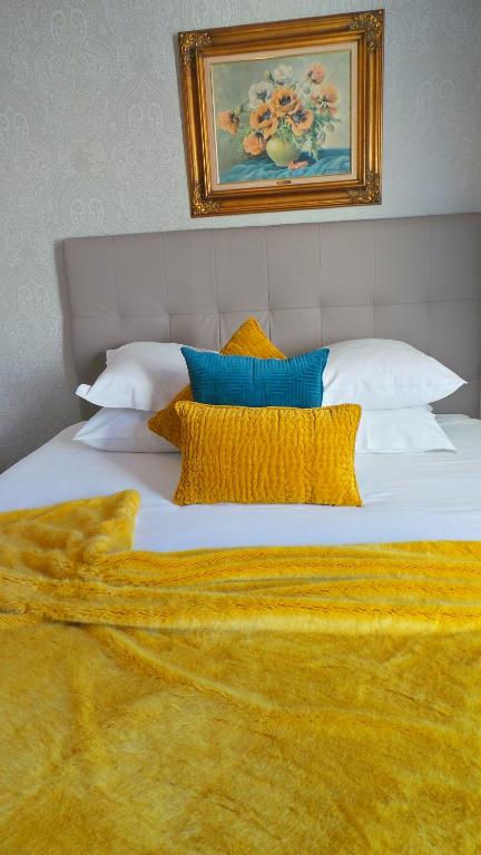 a large white bed with yellow pillows and a painting at Hotel Relais Du Postillon in Antibes
