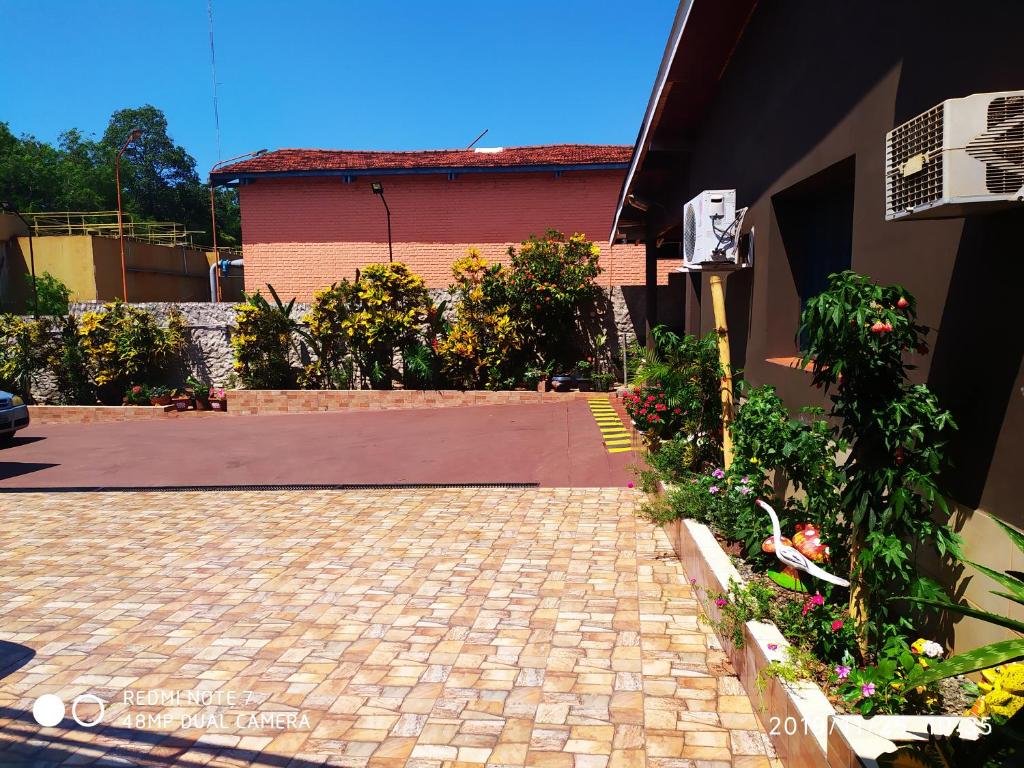 une allée en briques devant un bâtiment fleuri dans l'établissement Residencial Arcoiris, à Puerto Iguazú