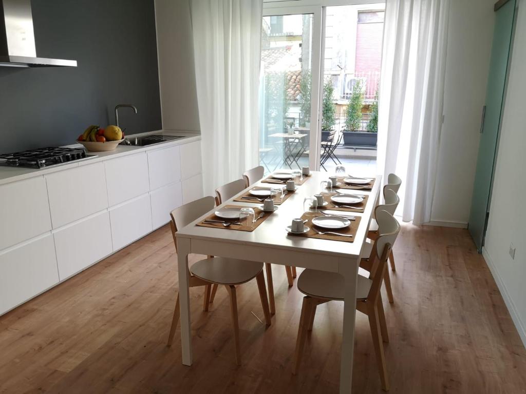 una mesa de comedor blanca con sillas y una cocina en ARMISI B&B en Catania