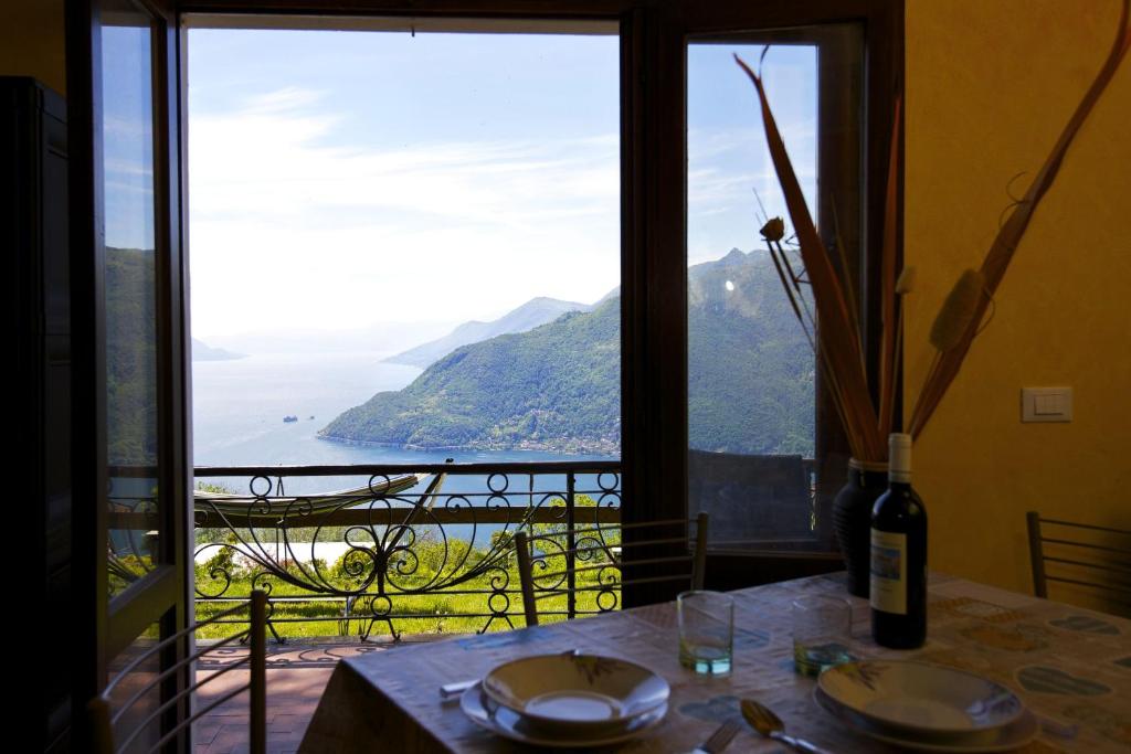 a table with a bottle of wine and a view of the ocean at Villetta Simonetta in Maccagno Superiore