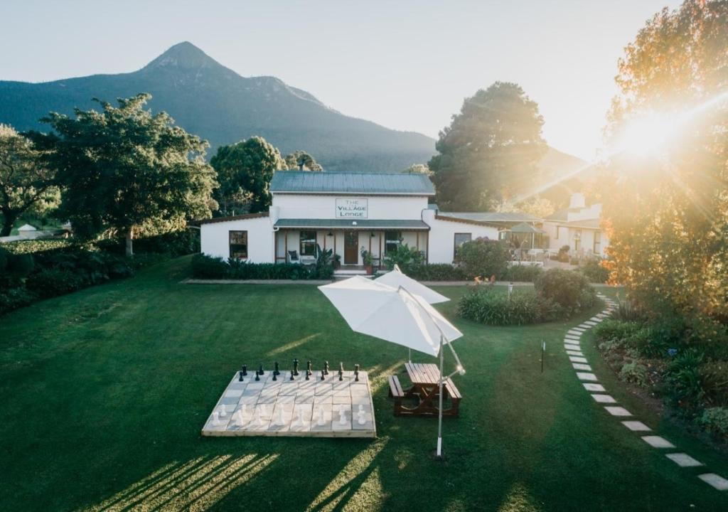 an umbrella and chairs in front of a building at The Village Lodge in Stormsrivier