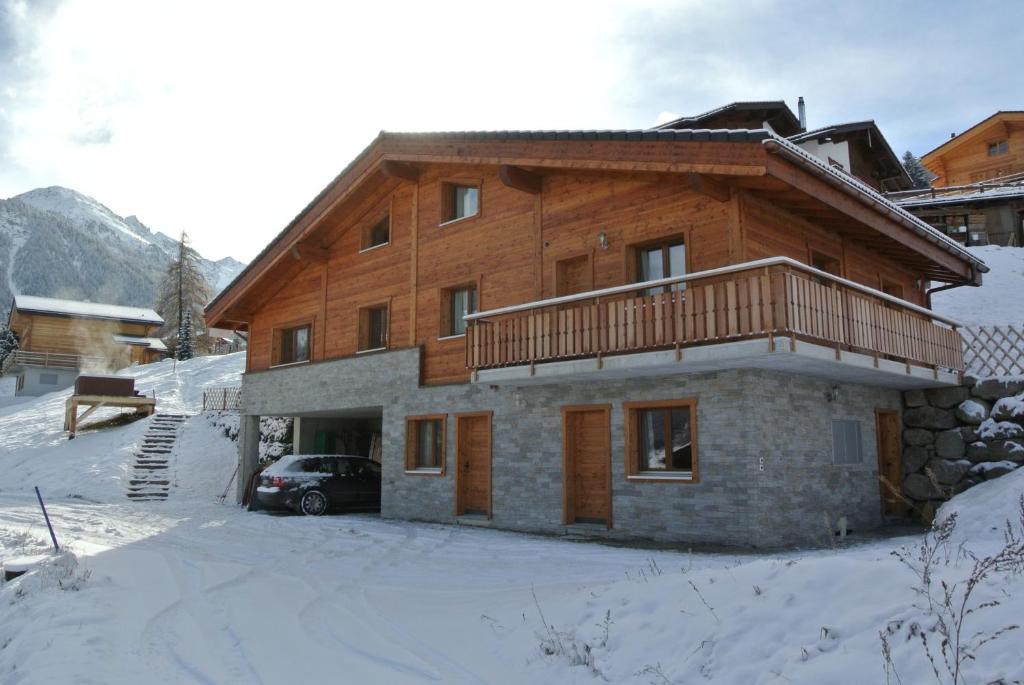 uma casa de madeira com uma varanda na neve em La Tzoum'hostel em La Tzoumaz