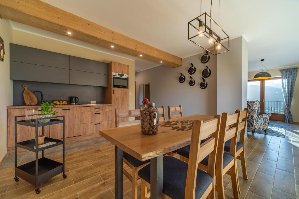 a kitchen and dining room with a wooden table and chairs at Apartamenty widokowe "u Homera" in Zakopane