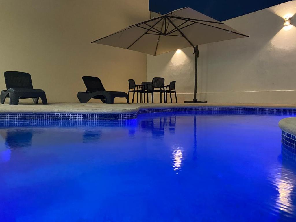 a swimming pool with chairs and an umbrella at Hotel Ambra in Playa del Carmen