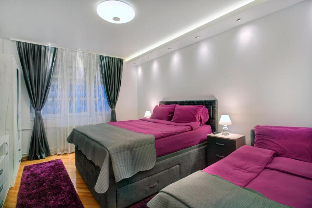 1 Schlafzimmer mit 2 Betten und lila Bettwäsche in der Unterkunft Balkanic Star Belgrade in Belgrad