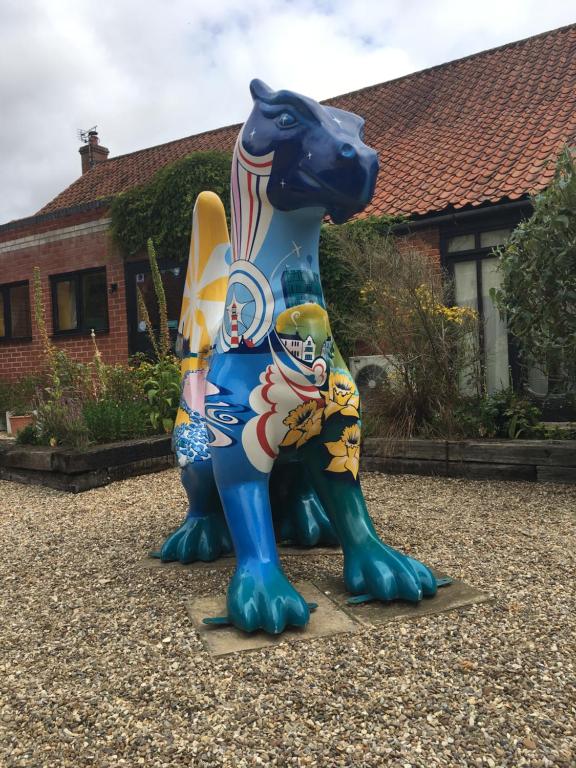 una estatua de un perro parado frente a una casa en The Orangery, en Thurning