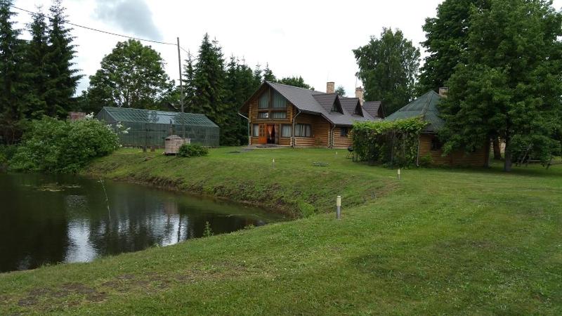 una casa di tronchi con un fiume di fronte di Upeslīči atpūtai a Jelgava
