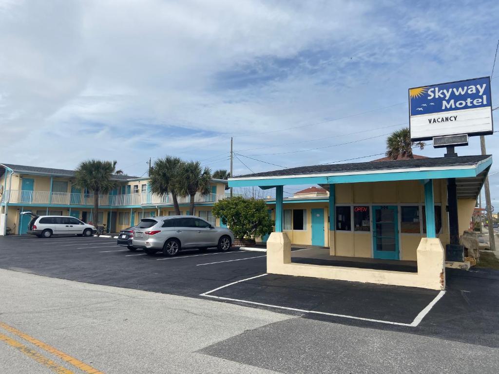 a six way motel with cars parked in a parking lot at Skyway Motel in Daytona Beach