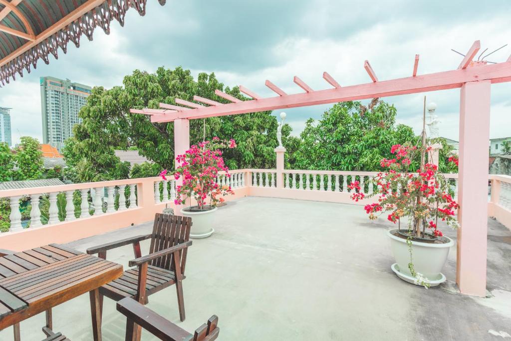 eine Terrasse mit 2 Bänken und einer Pergola mit Blumen in der Unterkunft Gaiwandhanat Homestay in Bangkok