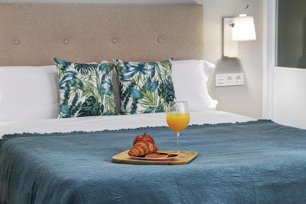 una bandeja de comida y un vaso de zumo de naranja en la cama en Apartamento Recogidas en Granada