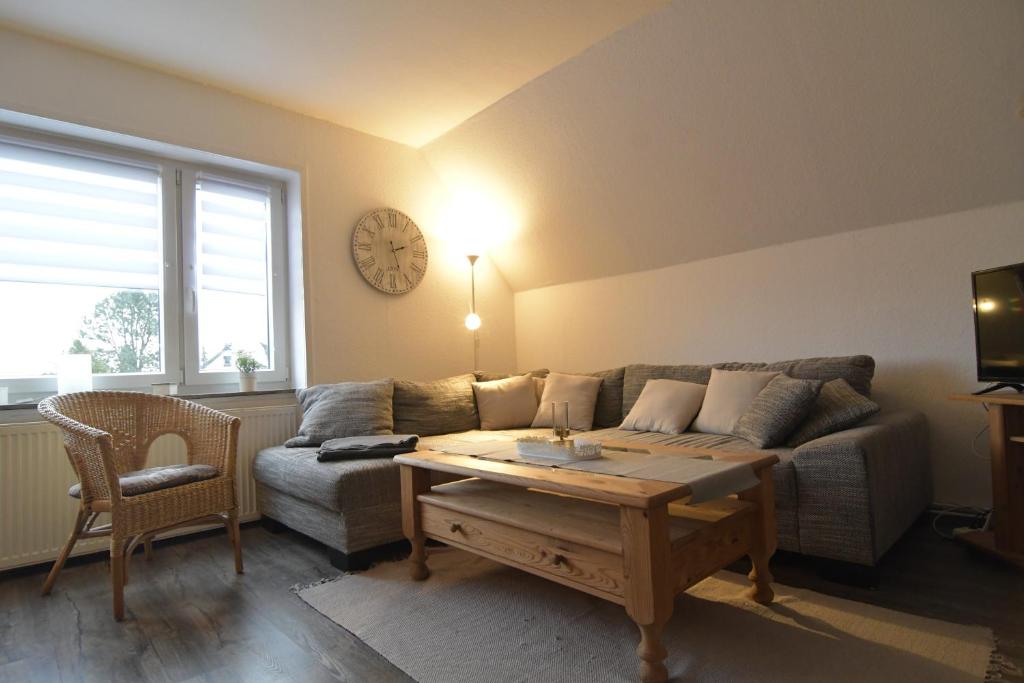 a living room with a couch and a table and a clock at Kleine Ferienwohnung Bederkesa in Bad Bederkesa