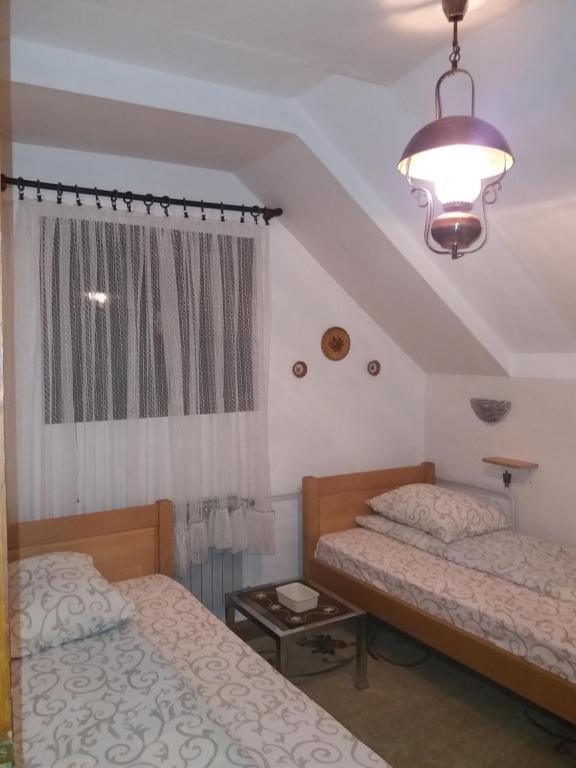 a bedroom with two beds and a lamp and a window at Apartments Beka in Žabljak