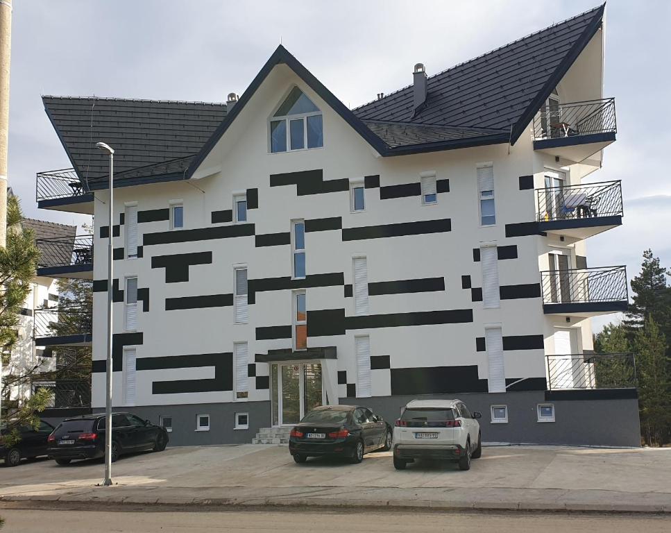 een gebouw met auto's geparkeerd op een parkeerplaats bij Apartman Mina Divcibare in Divčibare