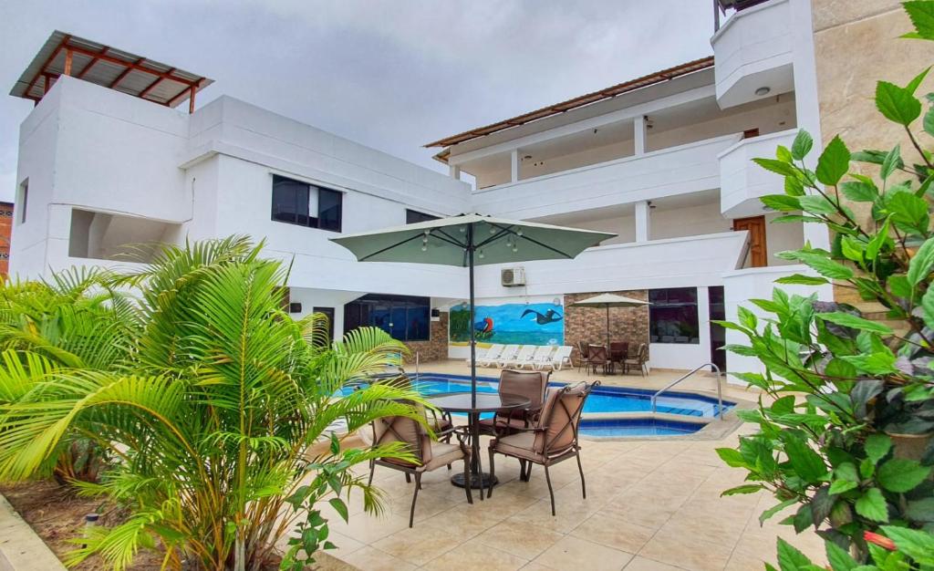 a patio with a table with an umbrella in front of a house at Buenavista Place Hotel in Bahía de Caráquez