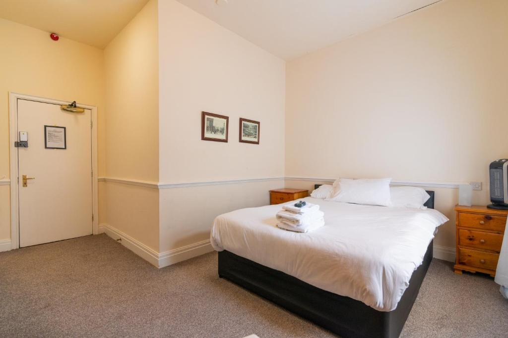 a bedroom with a bed with white sheets at Old Trafford Stadium Hotel in Manchester