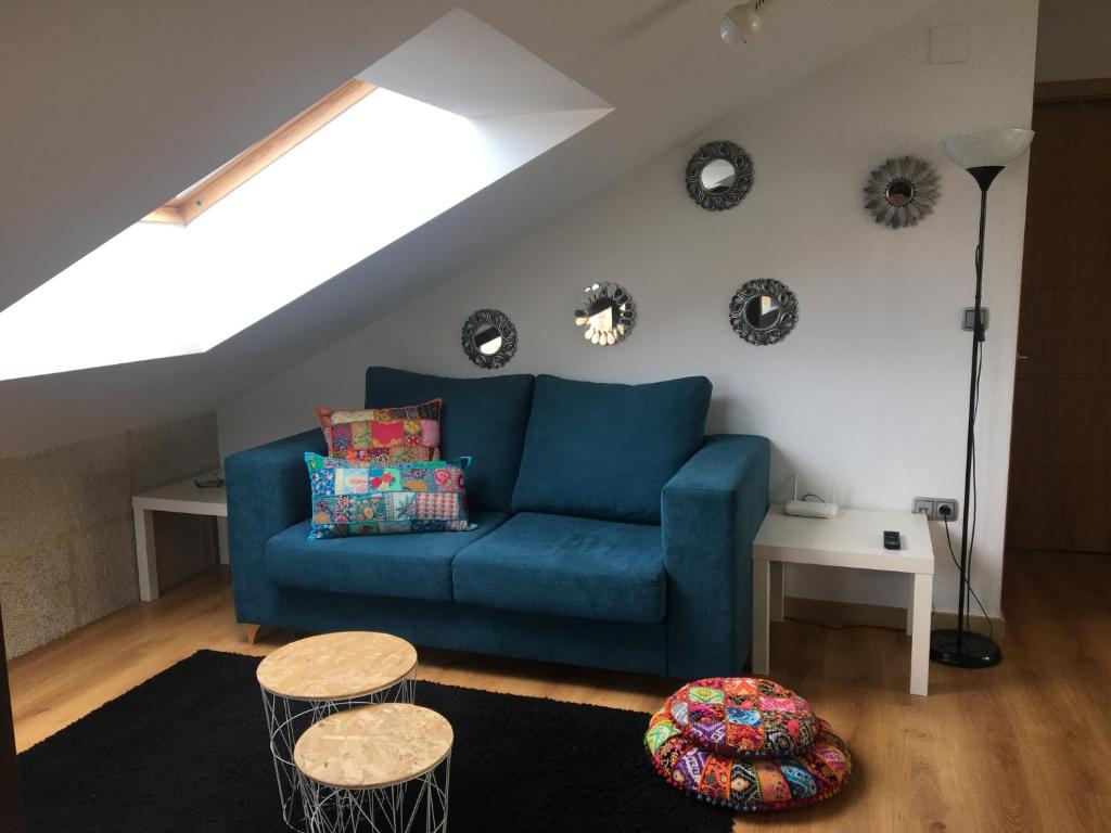 a living room with a blue couch and two tables at Ático Lobariñas in Allariz