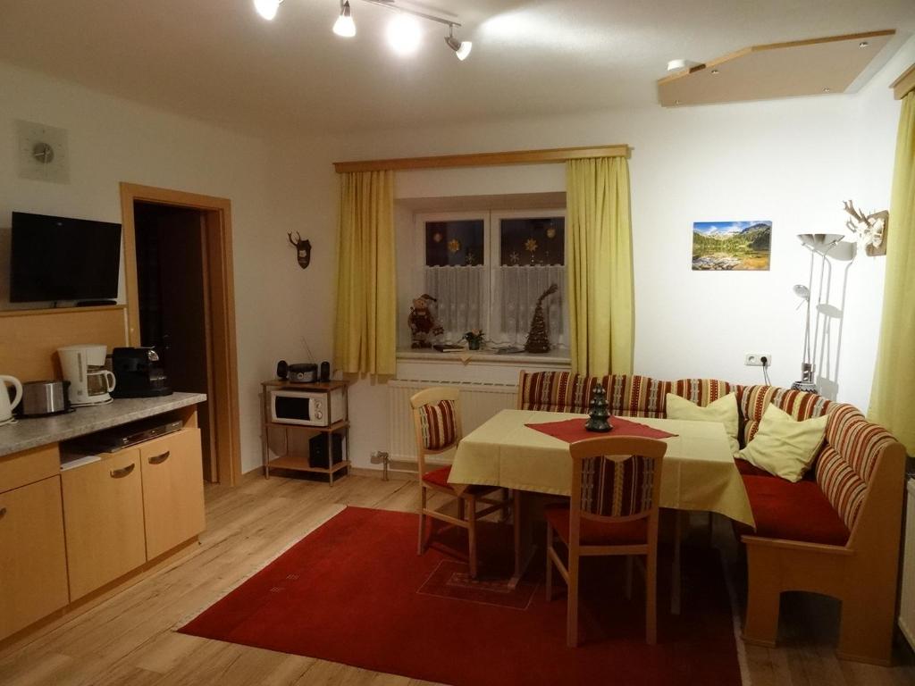 a living room with a dining room table and a kitchen at Landhaus Rathgeb in Bad Gastein