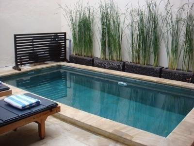 a swimming pool with a bench and plants on a wall at Villa Indah Kuta Royal - Private Pool - Optic Fiber High Speed Internet in Kuta